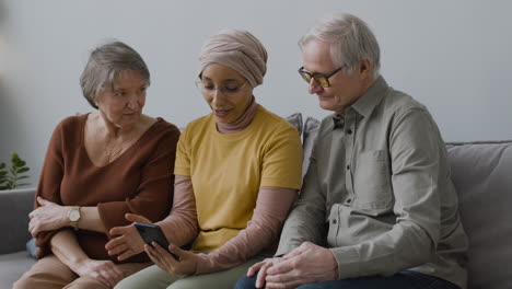 arabic woman teaching an elderly woman and man to use a smartphone