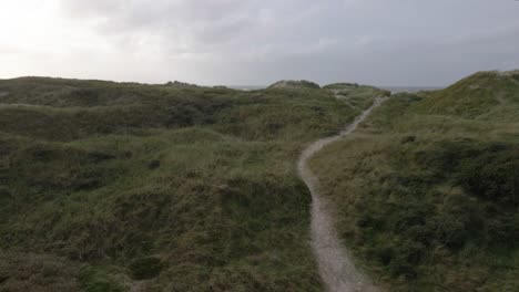un dron de baja altitud mira hacia el océano en hvide sande, dinamarca y se mueve lentamente hacia arriba, revelando la playa y el turbulento mar del norte, capturando el dramático paisaje costero en un día de tormenta