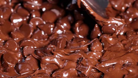 a spoon smoothly blends partially melted chocolate chips, creating a rich and glossy texture.