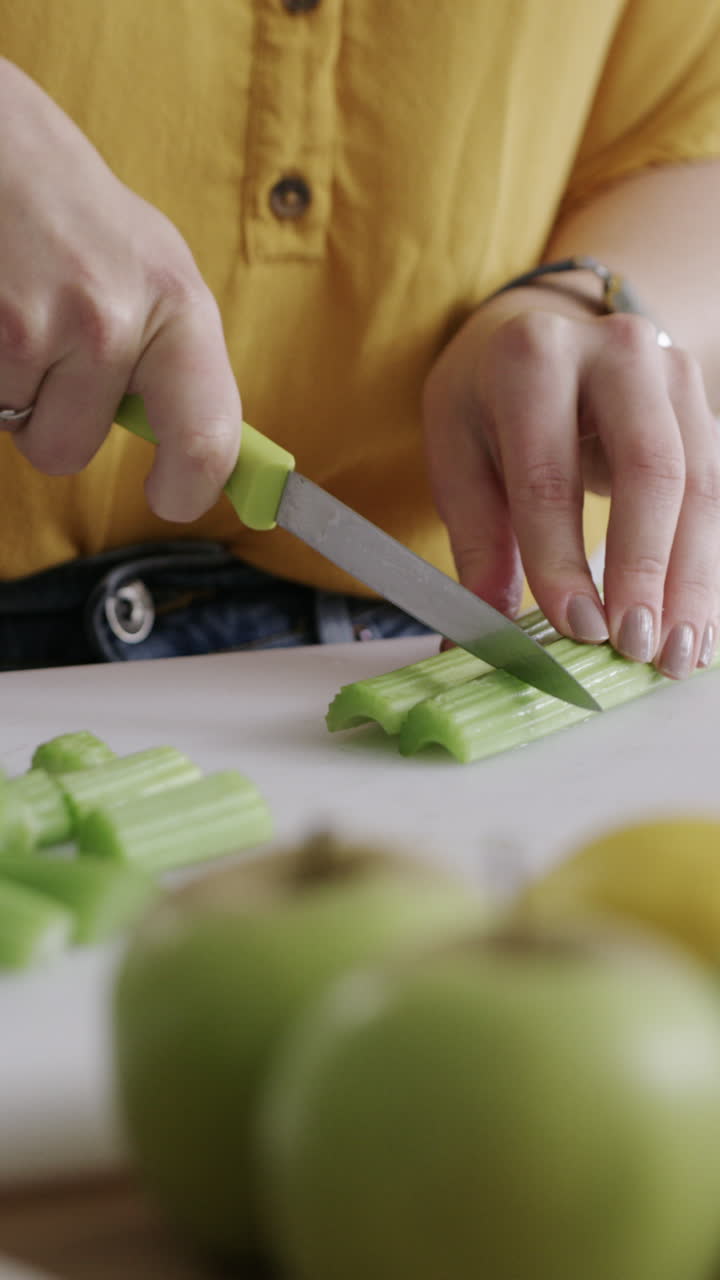 Primo piano di mani che tagliano sedano fresco in cucina