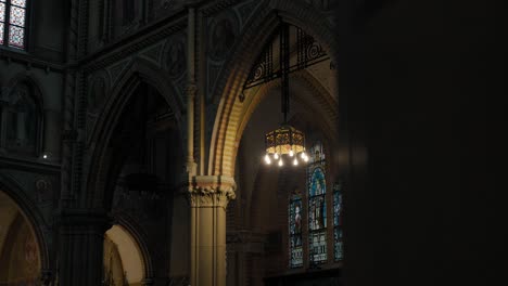 revealing shot inside a dimly lit church with stained glass windows and archways