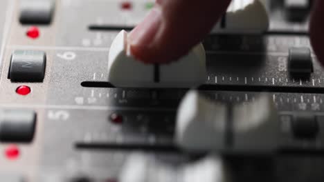 consola mezcladora, dedo en el fader de canal aumentando y disminuyendo gradualmente el nivel de una señal de audio