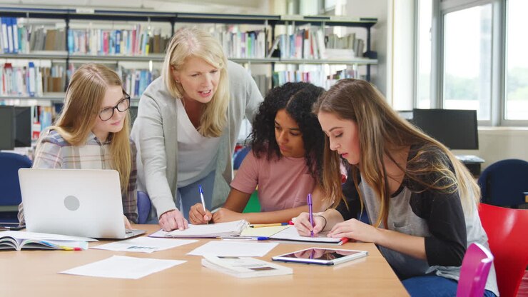 Tutor Working With Female College Students In Library