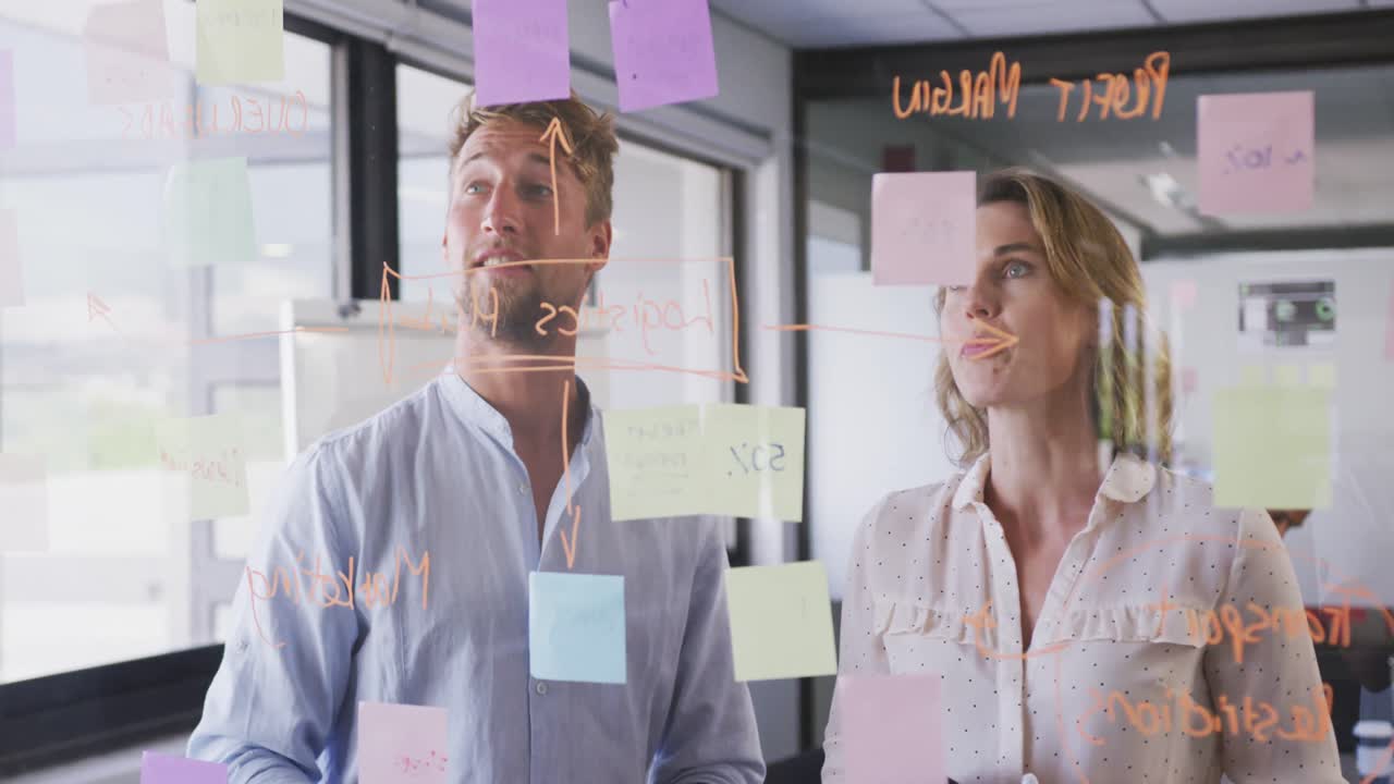 профессиональная бизнесвумен и бизнесмен обсуждают записки на стеклянной доске в современном офисе