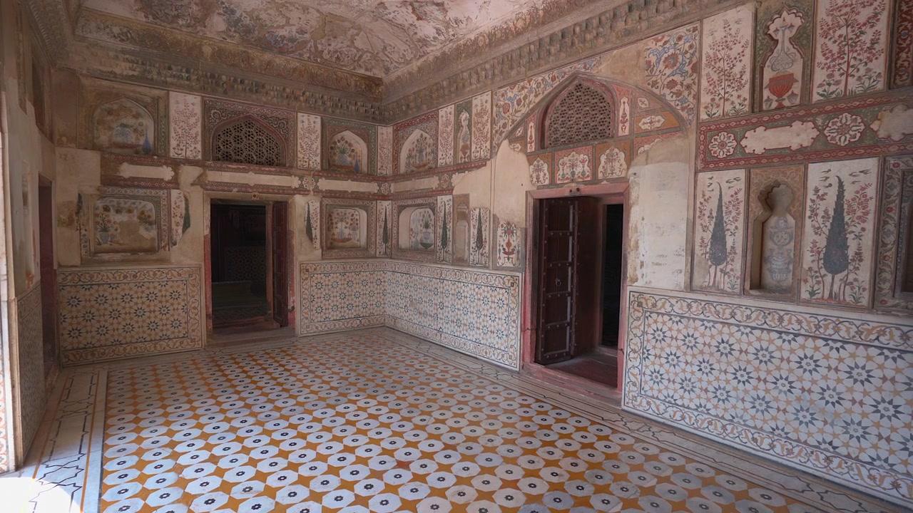 Panoramica lenta di una sala reale decorata, caratterizzata da intricati murales floreali e motivi geometrici di piastrelle, all'interno del Forte Amber a Jaipur, Rajasthan, India