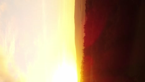 un dron vertical disparó una intensa puesta de sol ardiente en la naturaleza sobre bosques y campos