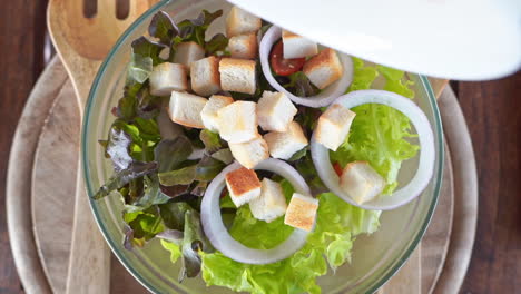 Overhead-shot-of-bacon-being-added-to-a-fresh-salad