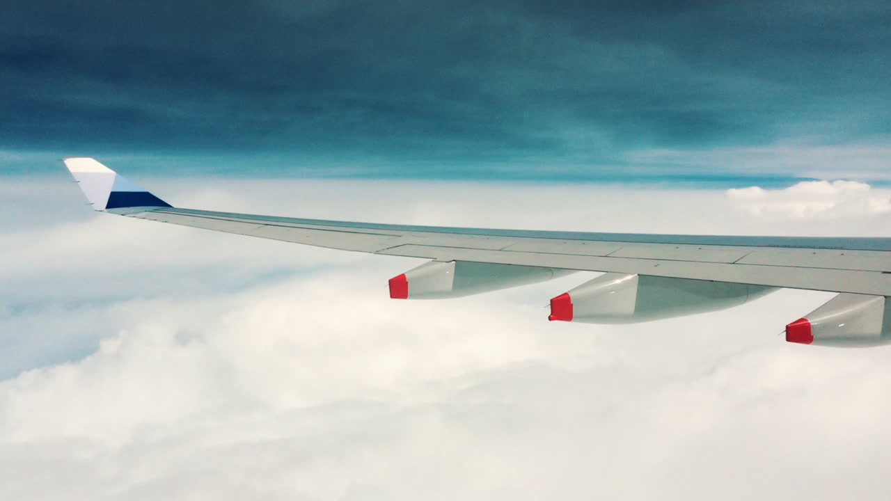 A beautiful HD quality of the window view of the airplane's left wing flying on top of the sea of cloud