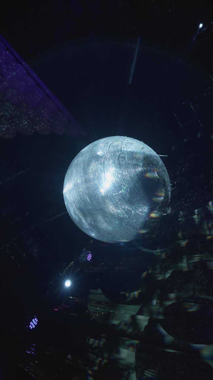 Vertical view of disco ball reflecting light in dark indoor event space