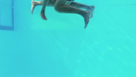 happy couple jumping in swimming pool together holding hands