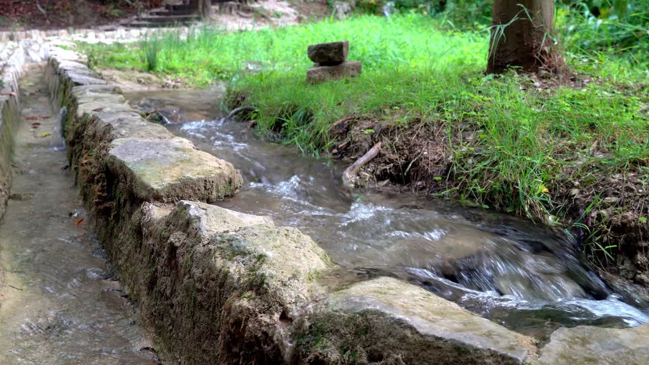 Water flowing next to a stone wall along a walkway at Krka National Park in Croatia