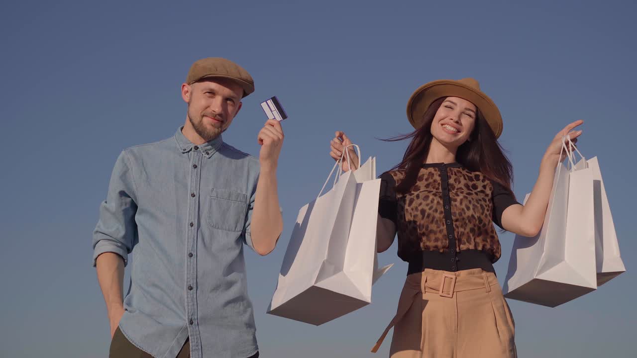 pareja de moda con tarjeta de crédito y bolsas de compras