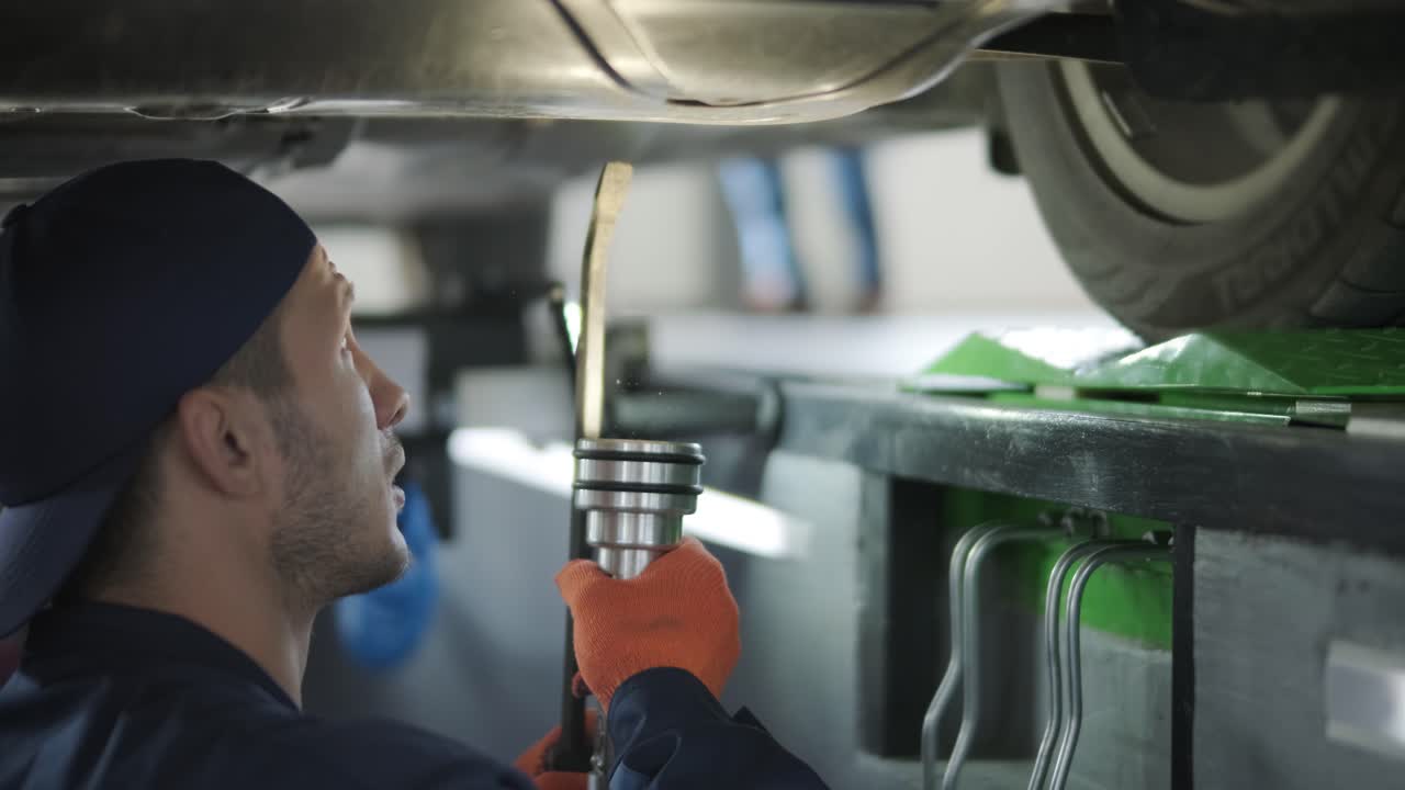 유니폼을 입은 기계공이 도구를 사용하여 차 부분을 수리하고 있습니다.