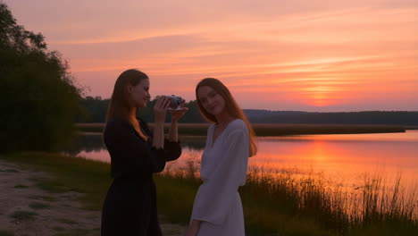 women taking photos by a lake at sunset