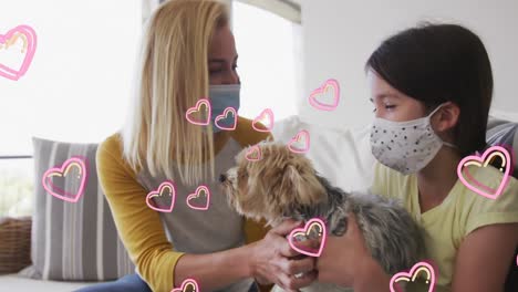 animación de corazones sobre mujer caucásica y su hija con máscaras faciales jugando con un perro mascota