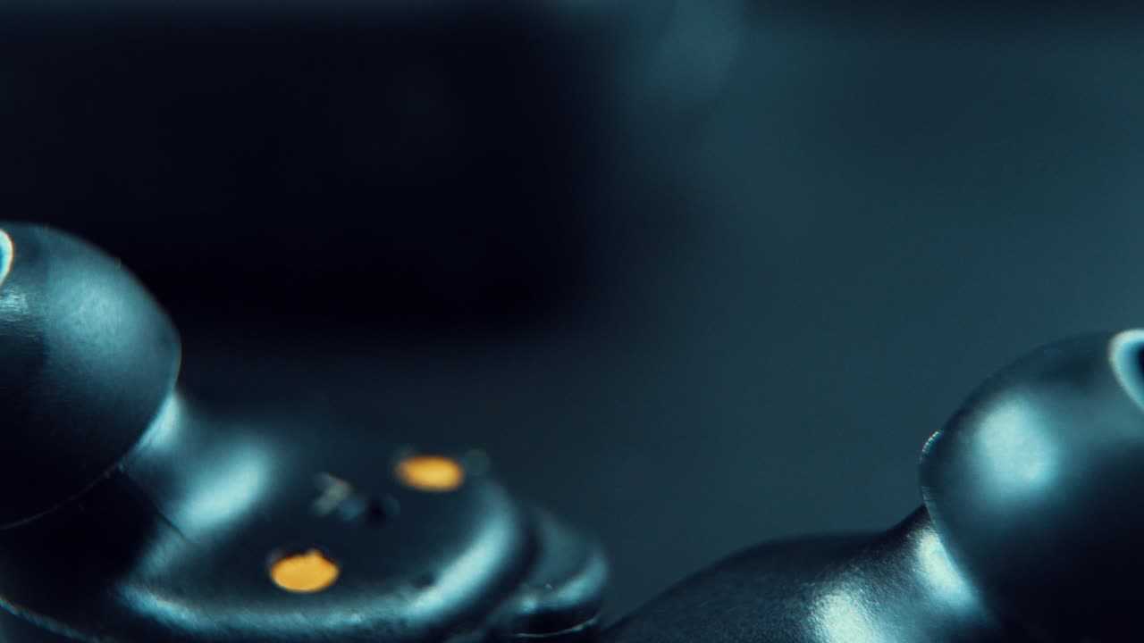 un zoom macro cinematográfico en una toma de un auricular negro inalámbrico auriculares boca abajo, iluminación de estudio, 120 fps, cámara lenta, full hd