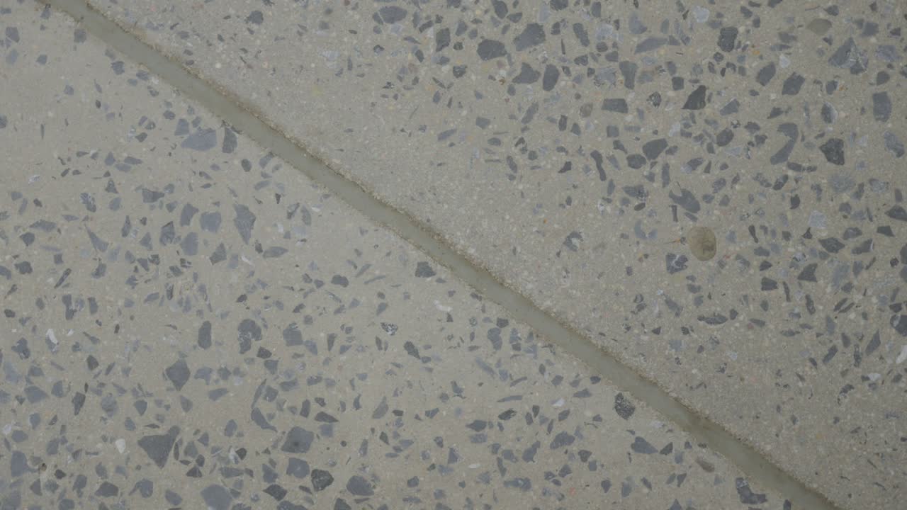La superficie in cemento terrazzo rivela aggregati maculati in primo piano.