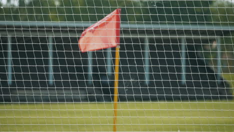 a football, soccer corner flag waving in an empty stadium behind a fence