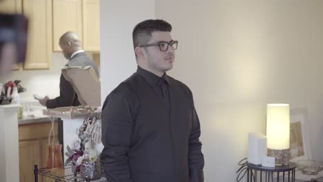 groom sits and listens to his friends talk as everyone gets ready for the wedding