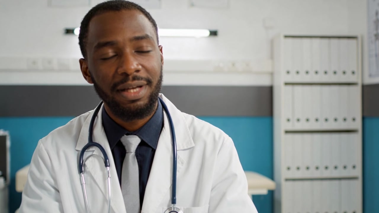 Un médecin en blouse blanche et stéthoscope répond à la question d'un patient dans une salle d'examen clinique.