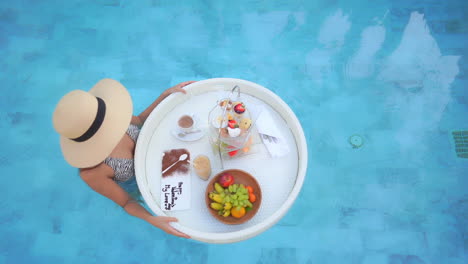 top view of sexy woman with hat holding floating exotic breakfast