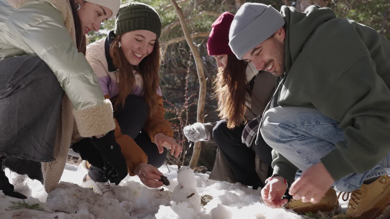 Group of friends building a snowman in winter