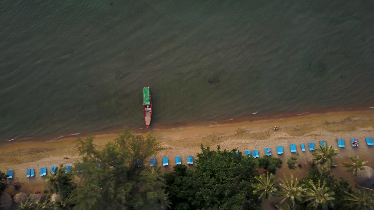 Aerial view of a tropical beach with boats and deck chairs