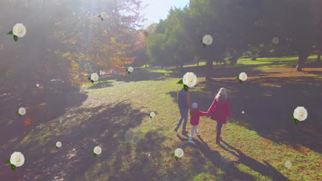 animation of flower icons over happy caucasian family in park