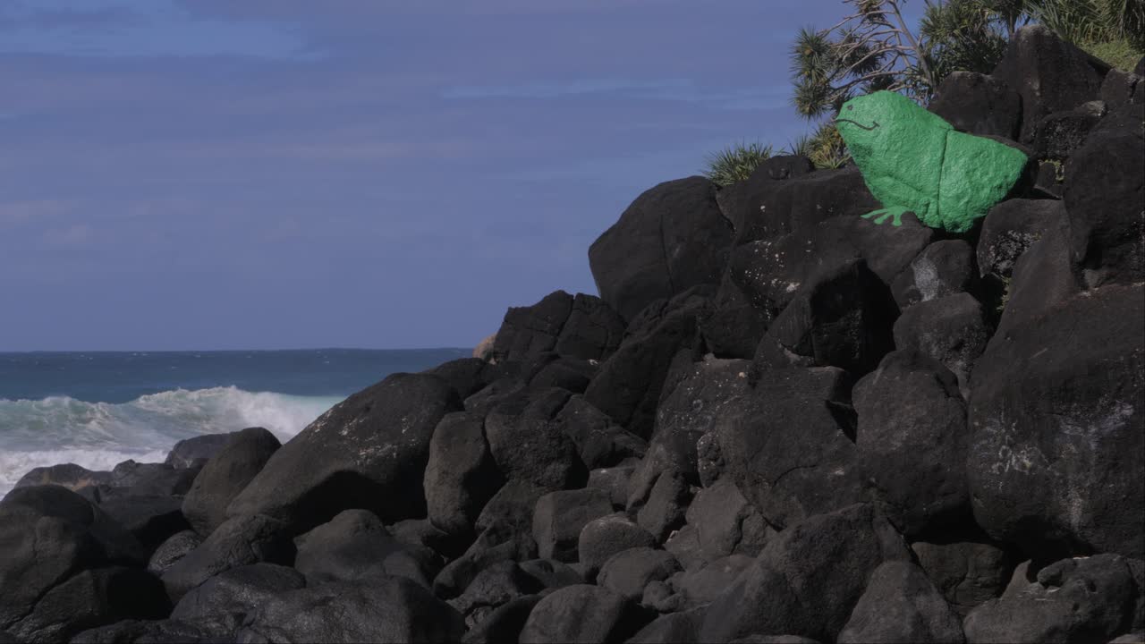 зеленая окрашенная каменная лягушка на пляже froggies возле скал snapper на побережье coolangatta в квинсленде, австралия