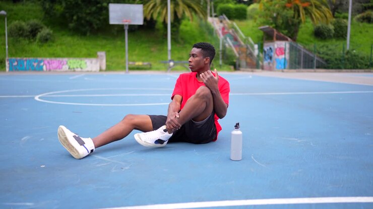Young Man Resting on a Basketball Court with Water Bottle