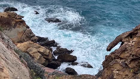 Meereswellen-Verlieren-Ihre-Kraft-Und-Krachen-Am-Strand-Gegen-Felsen,-Tagsüber-Eingefangen,-Konzept-Der-Unberührten-Natur