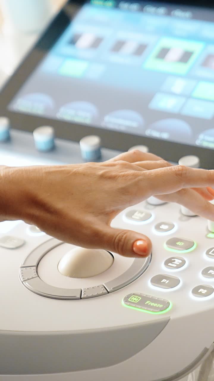 Doctor's hand operating the ultrasound machine. Unrecognized medic performs ultrasonic check up. Close up. Vertical video