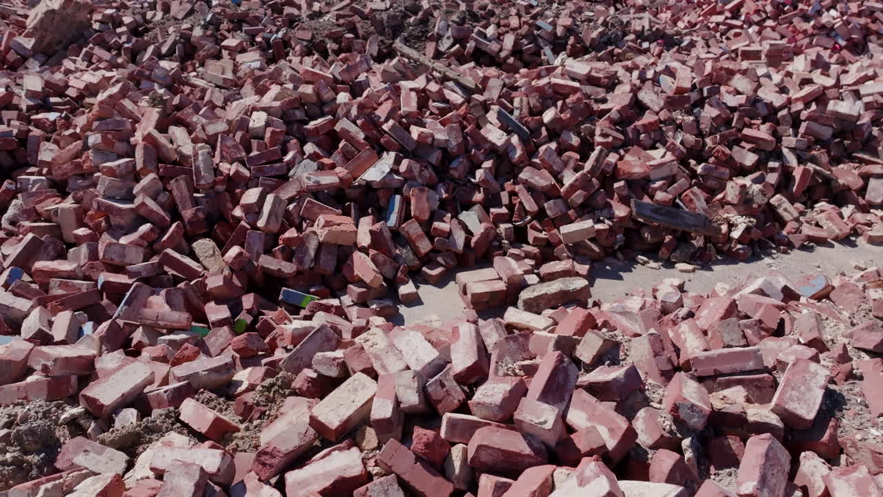 Close up aerial drone footage slowly moving over piles of red bricks.