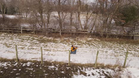 Man-with-rifle-walking-and-ducking-before-shooting,-aerial-follow-view