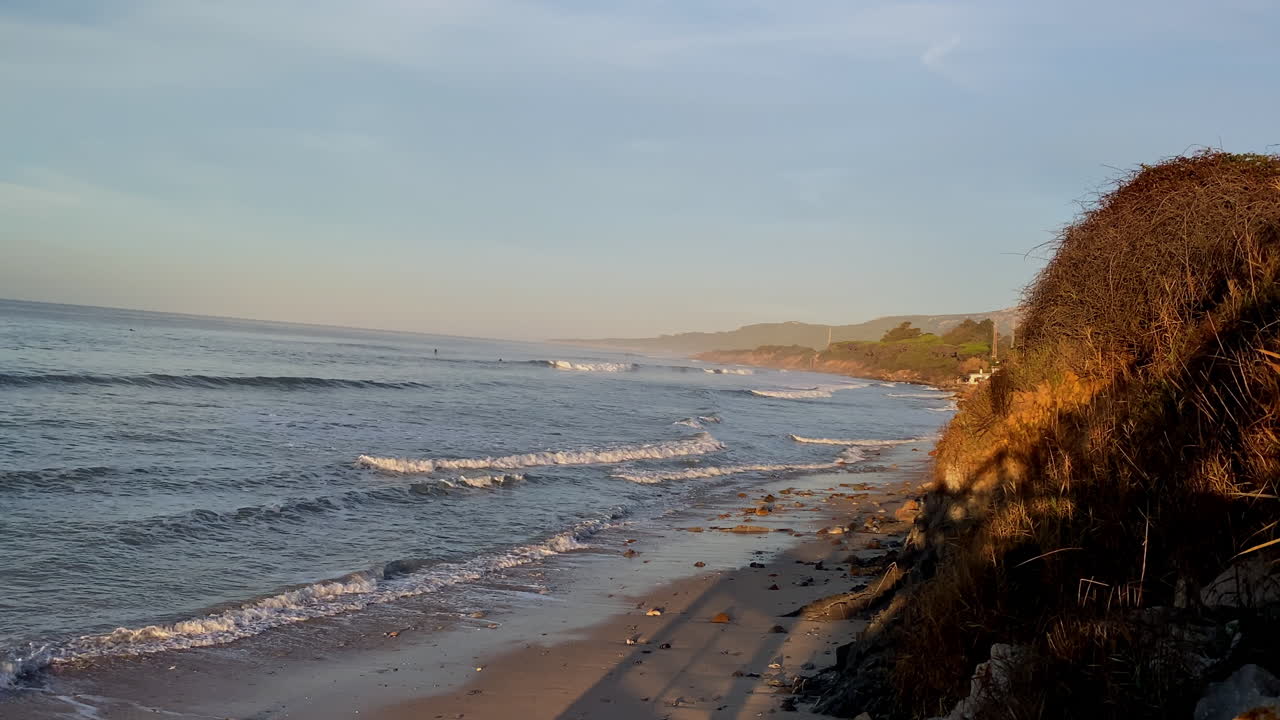 the Golden cliffs at Hurricane, Tarifa, catch the last light as gentle waves roll towards the beach at sunrise