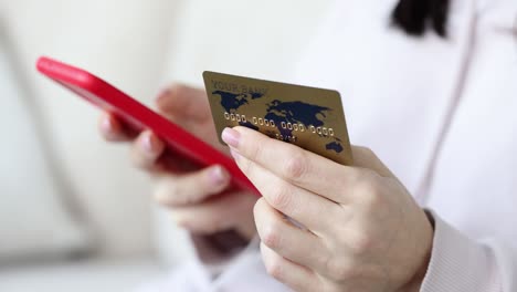 woman holds credit card and uses mobile phone