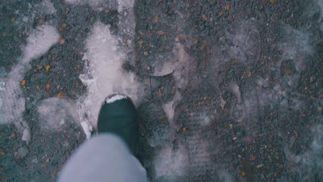 man legs walk along asphalt road with melted snow and sleek