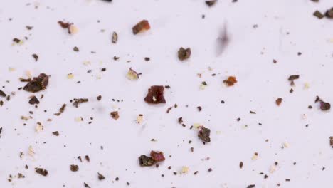 tiro macro de pimienta negra molida cayendo en superficie blanca