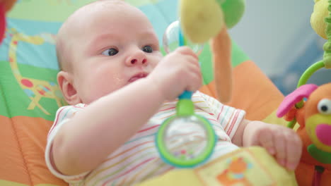 portrait of newborn kid playing with toy. close up of baby boy playing toy