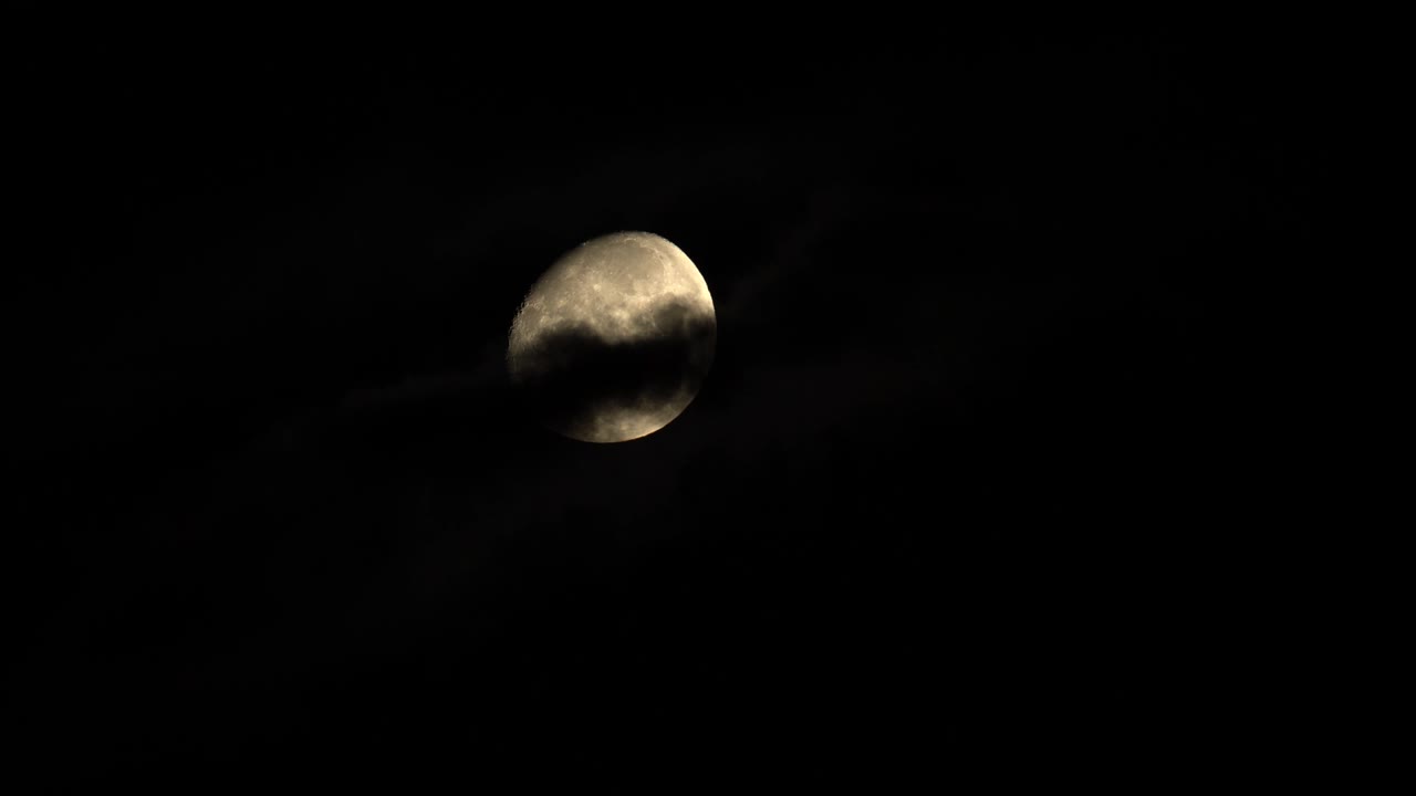 Full moon behind flowing clouds at night
