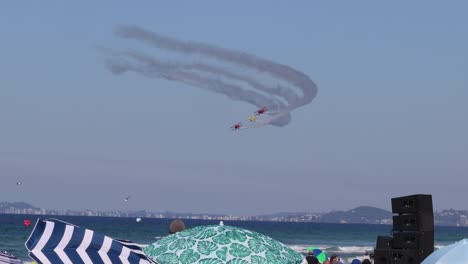 planes performing aerobatics over a beach audience