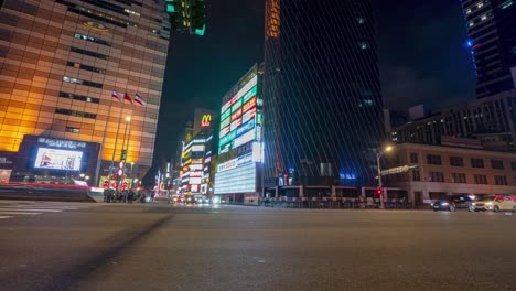 panning view of night city time lapse from left to right at zhongxiao west road busy intersection with traffic and pedestrians in metropolitan taipei taiwan.