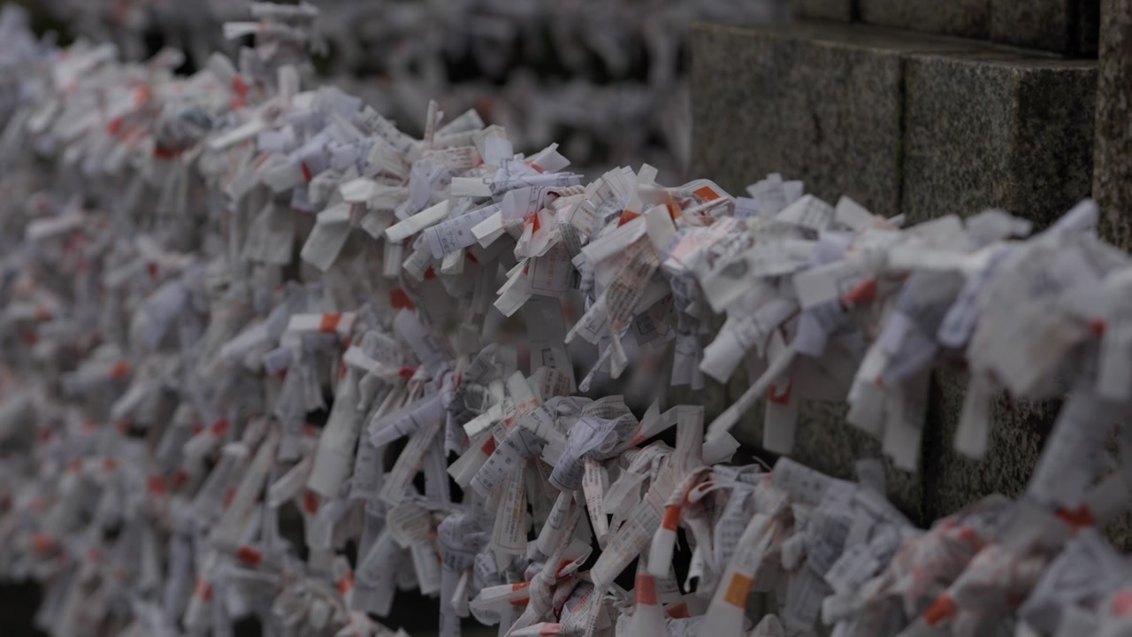 Dense rows of white folded omikuji fortune papers tied to stone wall at Japanese shrine