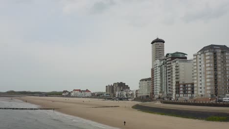 aerial retreat from the empty city beach in vlissingen, the netherlands with few seagulls flying in a frame at the end