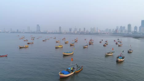 flying sideways with koliwada fishermen's boats parked in foreground while the mumbai city view in the back under a smog like hazy weather