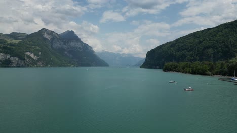 Boats sailing on the lake in front of a small village in G&auml;si Betlis, Walensee Glarus, Weesen Walenstadt, Switzerland- drone shot