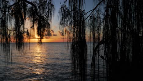 pan de cámara - puesta de sol y cielo nocturno sobre la laguna de fakarava, polinesia francesa, océano pacífico sur con reflexiones sobre la superficie del agua tranquila