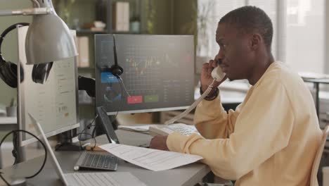 african american stock trader interacting with clients on phone
