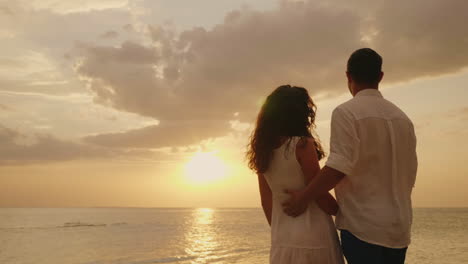 young couple in love embraces look together forward to the sunset by the sea back view hd video