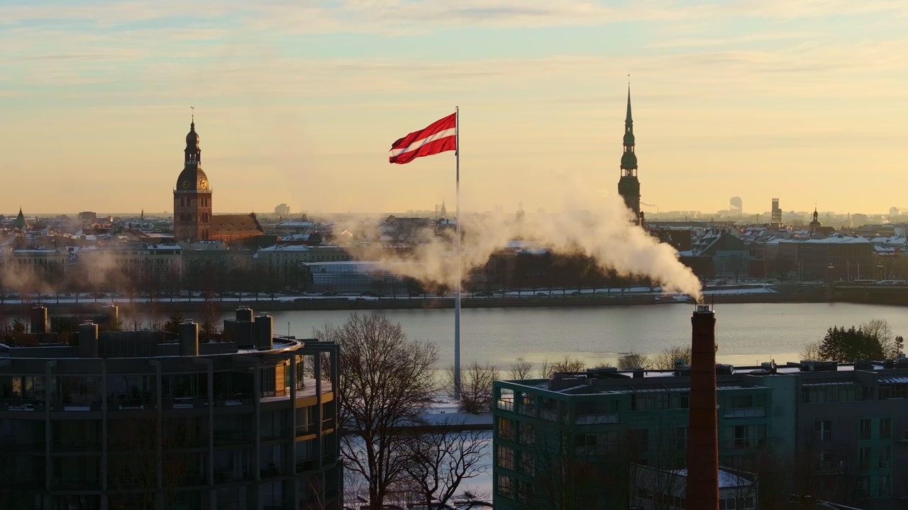 Aerial view of Riga skyline with Latvian flag and chimney smoke in winter light